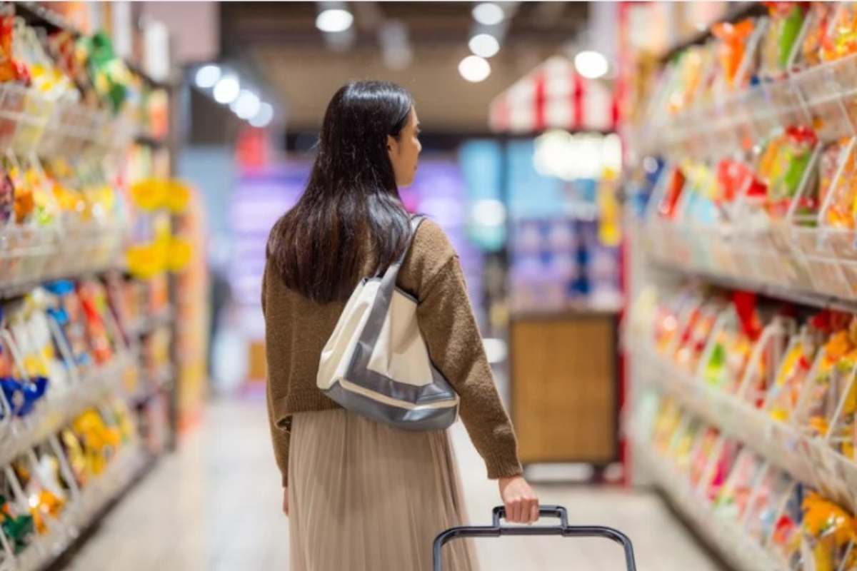 Donna cammina per le corsie del supermercato mentre fa la spesa 