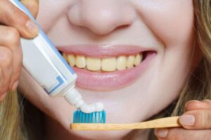 Persona con denti ingialliti che posiziona il dentifricio sullo spazzolino