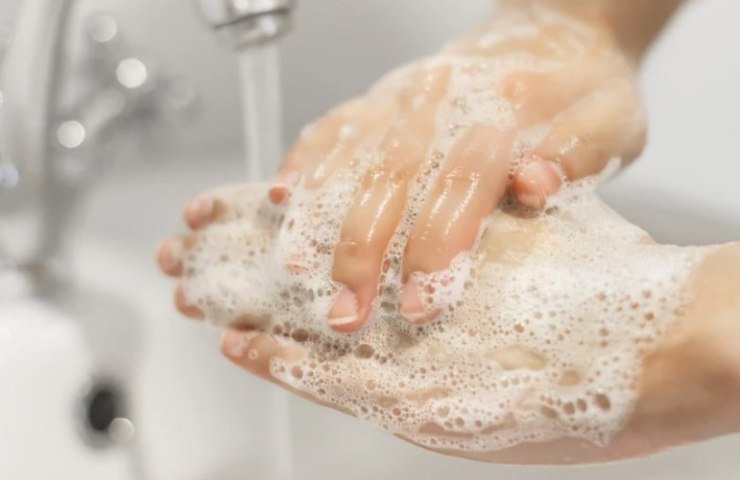 Persona si lava le mani con il sapone in un bagno 