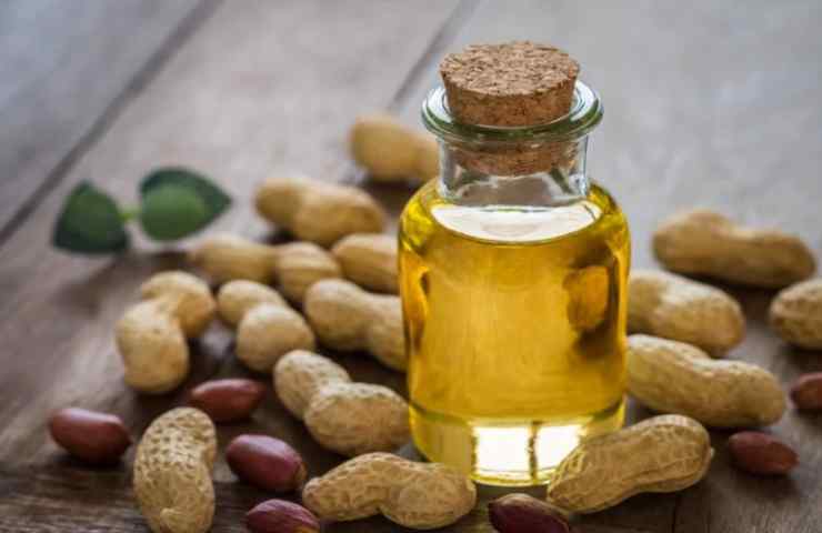 Olio in una bottiglia con molti arachidi sul tavolo 